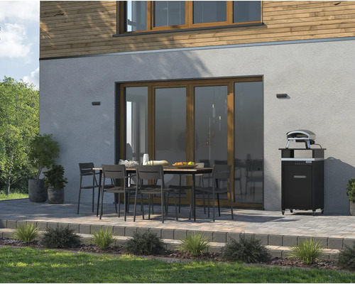 Buitenkant met eettafel, stoelen en pizzaoven voor een huismuur