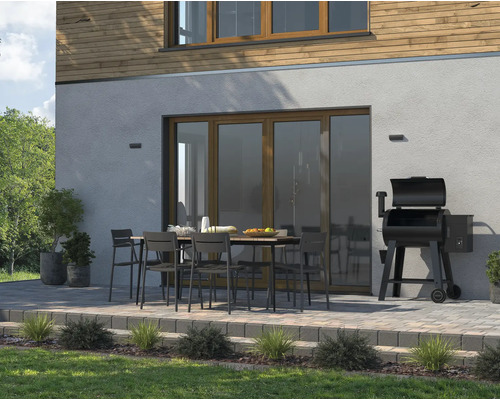 Buitenruimte met eettafel, stoelen en barbecue naast het huis