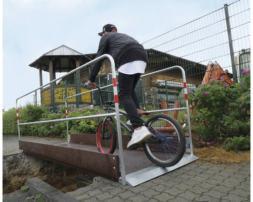 Een persoon rijdt op een BMX-fiets over een tijdelijke brug.