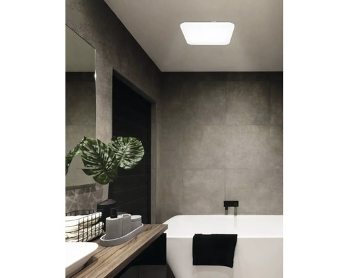 Badkamer met bad, wastafel en plafondlamp