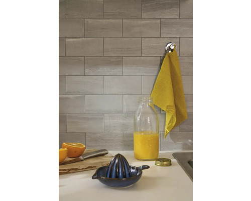 Grijze wandtegels in een keuken met een citruspers en een kan