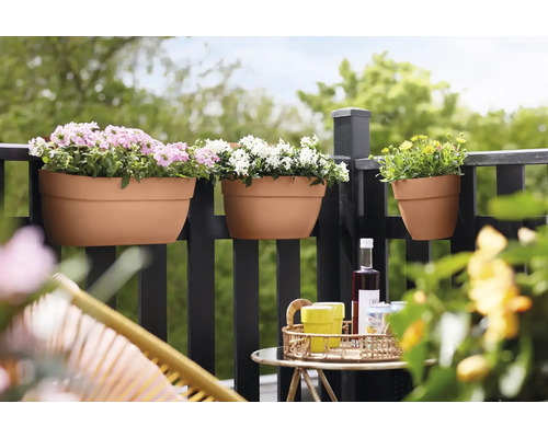 Bloembakken met planten aan een balkonreling, aangevuld met een tafel met drankjes.