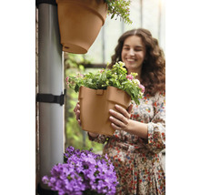 Vrouw houdt bloempot voor verticale tuinirrigatie in haar handen