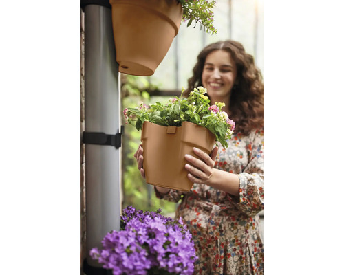 Vrouw houdt bloempot voor verticale tuinirrigatie in haar handen