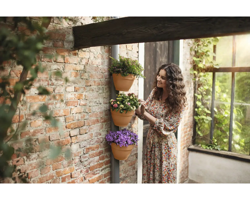 Vrouw bekijkt gestapelde bloempotten aan de muur.