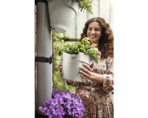 "Vrouw houdt een grijze bloempot met bloemen in haar handen