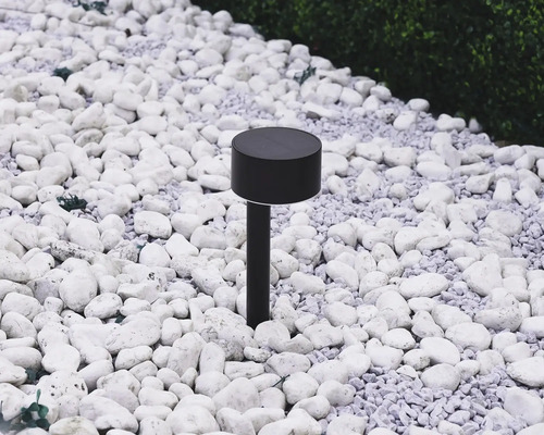 Zwarte solarlamp in de tuin tussen witte stenen