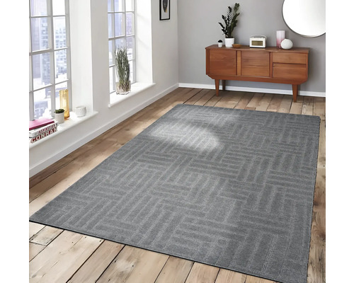 Grijs vloerkleed met geometrisch patroon in een lichte kamer op een houten vloer