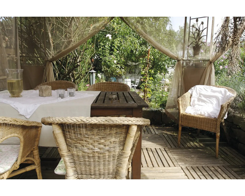 Gedecoreerde tuintafel met rotan stoelen in een lichte, vriendelijke sfeer.