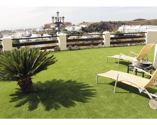 Scene met kunstgras, ligstoelen en een kleine boom op een balkon met uitzicht op een stad.