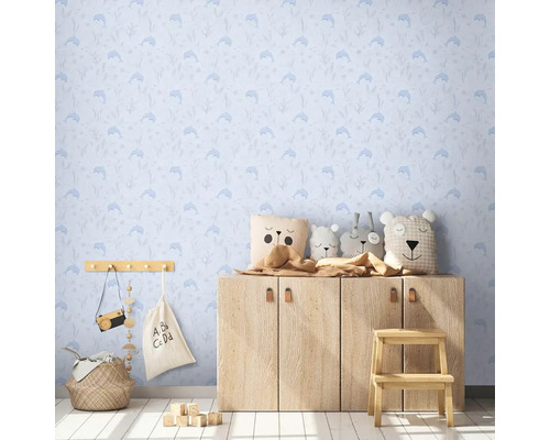 Kinderkamer met blauw dolfijnenbehang, houten commode en knuffels.