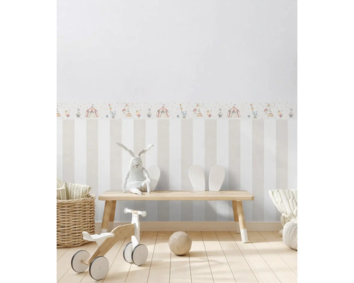 Kinderkamer met gestreept behang, circusrand, speelgoed en houten bank.