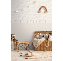Gedecoreerde kinderkamer met wolkenbehang, regenboog wanddecoratie, rotan krukje en speelgoed in een mand.
