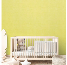 Babykamer met ledikant, teddybeer en decoratieve elementen voor een lichtgele muur