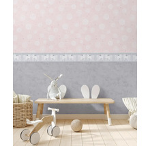 Kinderkamer met roze behang, speelgoed en een klein houten bankje.