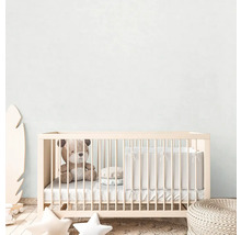 Een kinderkamer met een babybedje, een teddybeer en decoraties.
