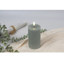 Decoratieve LED stompkaars met planten en een schriftrol op een beige doek