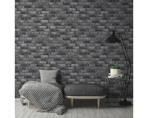 Interieur met een bakstenen behang, een bank met kussens en een staande lamp