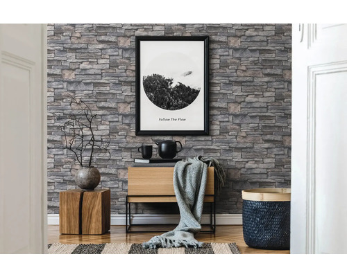 Woonkamer met stenen behang, commode en decoraties voor een gezellige sfeer.