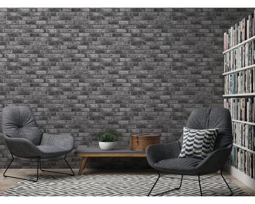 Woonkamer met bakstenen behang, fauteuils en boekenkast voor een gezellige sfeer.