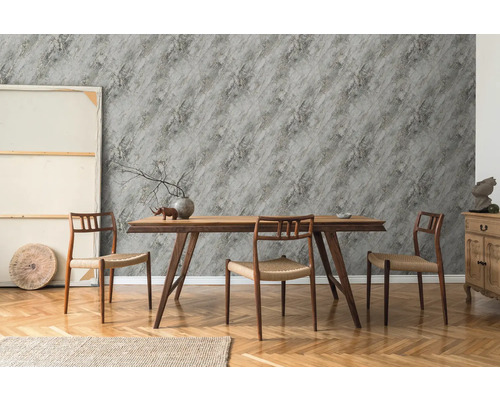 Eetkamer met houten tafel, stoelen en grijs behang met steeneffect.