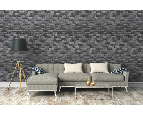Woonkamer met grijs bakstenen behang, bank, staande lamp en salontafel