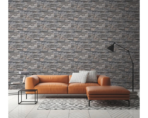 Woonkamer met grijs steenmotief behang, bank en lamp.