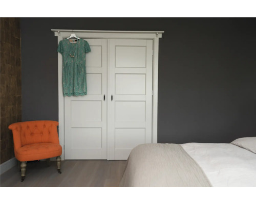 Slaapkamer met tweepersoonsbed, kledingkastdeuren en fauteuil