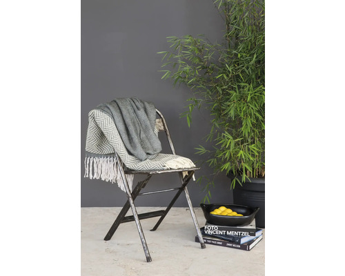 Decoratieve opstelling met deken op stoel en bamboeplant in pot