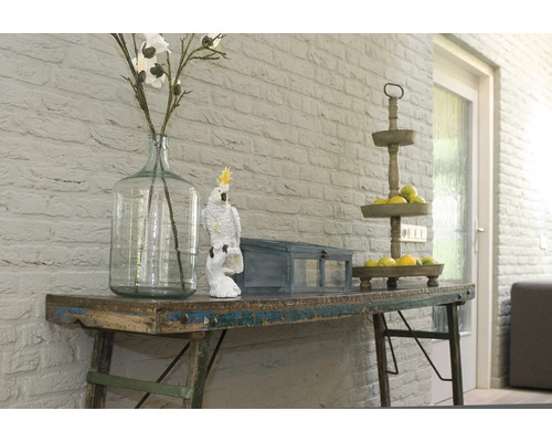 Decoratieve schikking op een tafel met vaas, papegaaibeeldje en etagère.