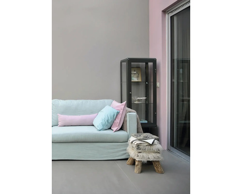 Lichte woonkamer met bank, kussens, vitrinekast en kruk