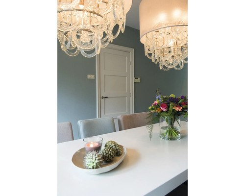 Eetkamer met glazen kroonluchters, eettafel, bloemen en decoratie