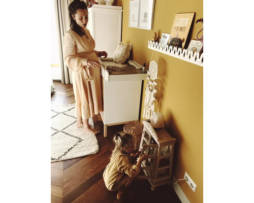 Kamer met commode, plank, decoratie en spelend kind.