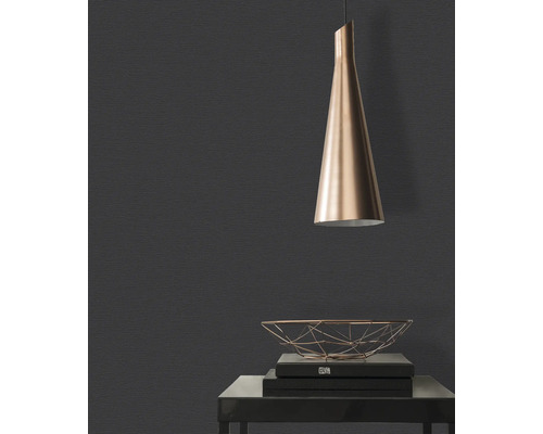 Close-up van een donkere muur met structuurbehang, een hanglamp en een decoratieve metalen mand op een tafel