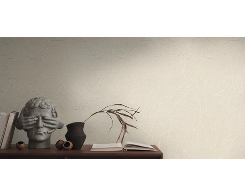 Woonkamer met patroonbehang, stapel boeken en decoratieve objecten op een dressoir