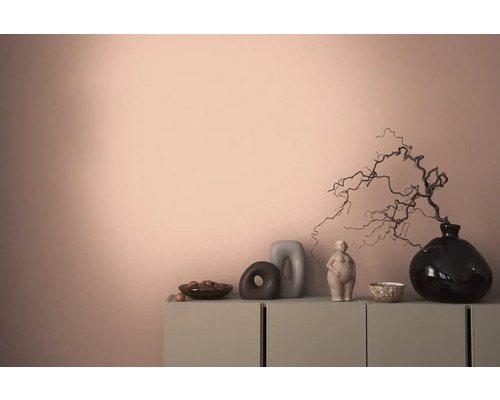 Decoratief interieur met een dressoir, vazen en sculpturen tegen een gekleurde wand.