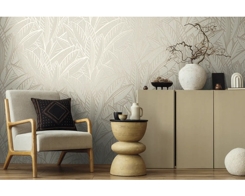 Woonkamer met fauteuil, bijzettafel en kast tegen een muur met een bladmotief behang