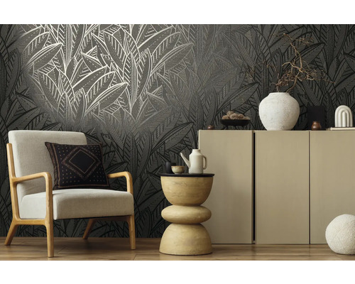 Woonkamer met fauteuil, bijzettafel en kast voor een behang met patroon.