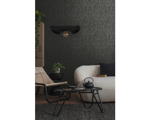 Woonkamer met bank, stoel, tafel, hanglamp en behang met print.