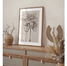 Decoratieve afbeelding met een palmmotief in een houten frame, geplaatst op een dressoir.