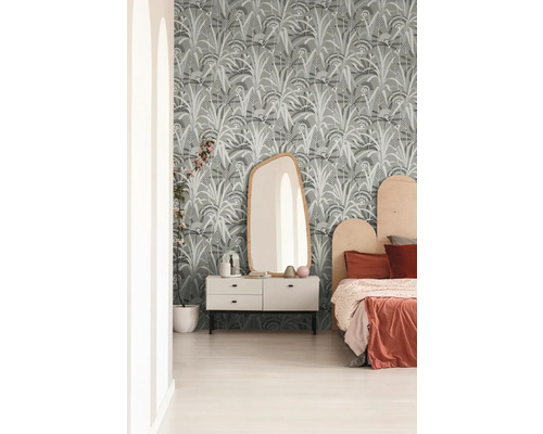 Slaapkamer met patroonbehang, ladekast, spiegel en bed