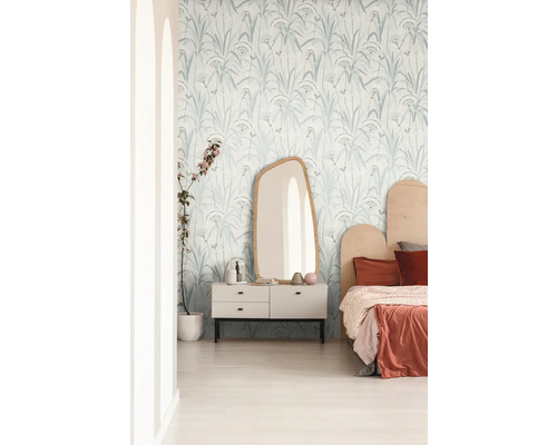 Lichte slaapkamer met behang met plantenmotief, spiegel en ladekast.