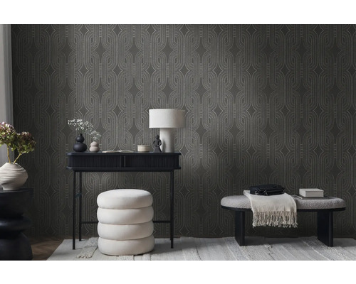 Woonkamer met patroonbehang, bureau, lamp en zitplaatsen.