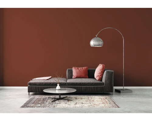 Woonkamer met bank, vloerlamp en tapijt op betonnen vloer voor een bruine muur