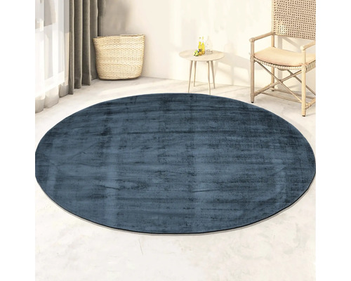 Blauw rond vloerkleed in een lichte kamer met mand en tafel