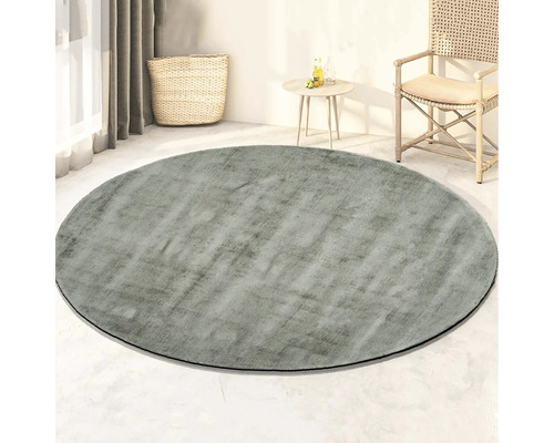 Rond vloerkleed in de woonkamer met mand, bijzettafel en stoel.