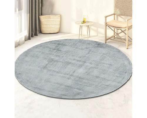 Rond vloerkleed in woonkamer met rotan stoel en bijzettafel