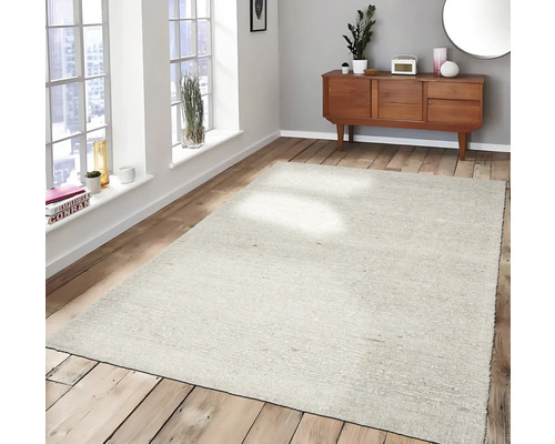 Lichtgekleurd, geweven vloerkleed op houten vloer in een woonkamer