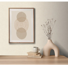 Decoratieve opstelling met een ingelijste afbeelding met abstract cirkelmotief, een vaas met droogbloemen, een kop en boeken op een tafel.