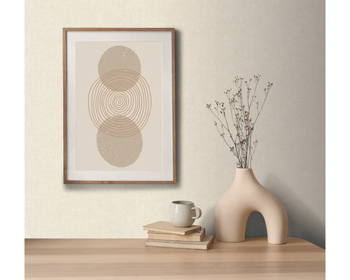 Decoratieve opstelling met een ingelijste afbeelding met abstract cirkelmotief, een vaas met droogbloemen, een kop en boeken op een tafel.